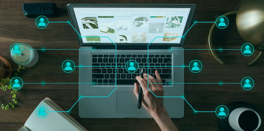 Zu sehen ist ein Laptop aus der Vogelperspektive. Auf dem Bild sind holografische Linien die ein Netzwerk darstellen